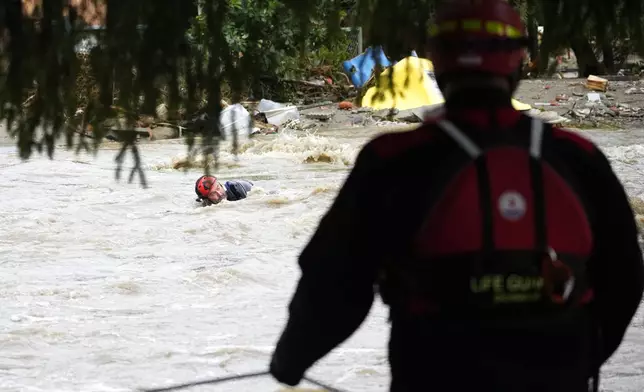 A rescue worker struggles against a strong current during an evacuation operation during floods in Jesenik, Czech Republic, Sunday, Sept. 15, 2024. (AP Photo/Petr David Josek)