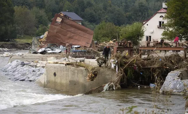 A man barrows out mud as residents return to clean up after recent floods in Mikulovice, Czech Republic, Thursday, Sept. 19, 2024. (AP Photo/Petr David Josek)