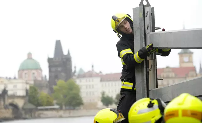 Firefighters adjust parts of the anti-flood barriers in Prague, Czech Republic, Friday, Sept. 13, 2024. (AP Photo/Petr David Josek)