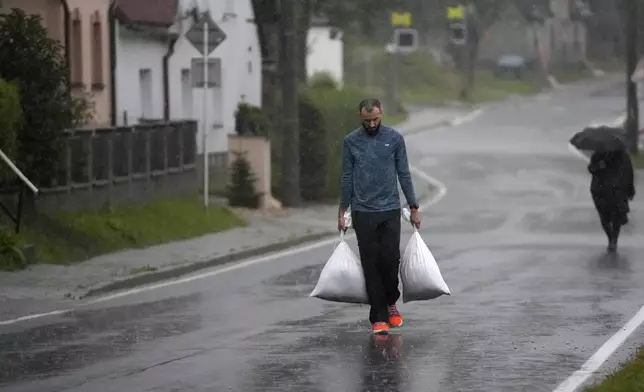 A resident carries sandbags to protect his house during floods Jesenik, Czech Republic, Sunday, Sept. 15, 2024. (AP Photo/Petr David Josek)