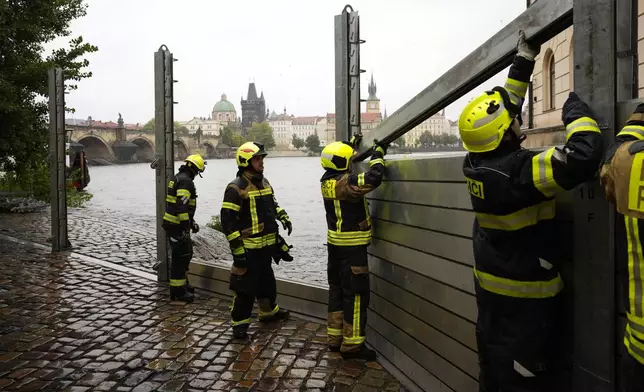 Firefighters adjust parts of the anti-flood barriers in Prague, Czech Republic, Friday, Sept. 13, 2024. (AP Photo/Petr David Josek)