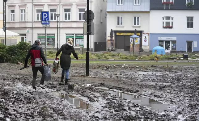 Resident struggle through mud after recent floods in Jesenik, Czech Republic, Monday, Sept. 16, 2024. (AP Photo/Petr David Josek)