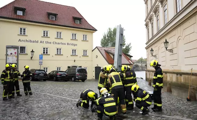 Firefighters adjust parts of the anti-flood barriers in Prague, Czech Republic, Friday, Sept. 13, 2024. (AP Photo/Petr David Josek)