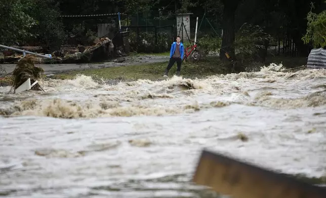 A resident looks at the river during floods in Jesenik, Czech Republic, Sunday, Sept. 15, 2024. (AP Photo/Petr David Josek)