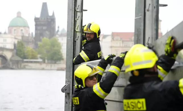 Firefighters adjust parts of the anti-flood barriers in Prague, Czech Republic, Friday, Sept. 13, 2024. (AP Photo/Petr David Josek)