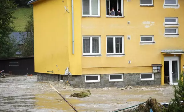 Residents look out from a window of their flooded house in Jesenik, Czech Republic, Sunday, Sept. 15, 2024. (AP Photo/Petr David Josek)