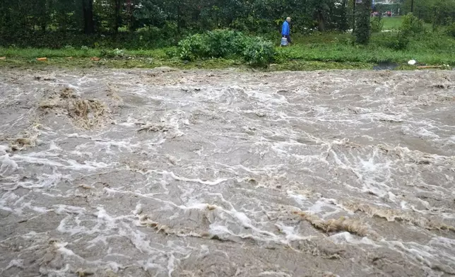 A resident carries bottles of water during floods in Jesenik, Czech Republic, Sunday, Sept. 15, 2024. (AP Photo/Petr David Josek)