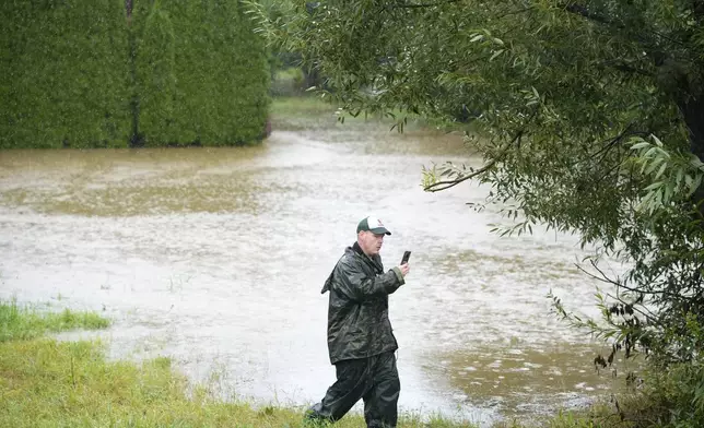 A residents takes a photo as the Opava river rises near Brantice, Czech Republic, Saturday, Sept. 14, 2024. (AP Photo/Petr David Josek)