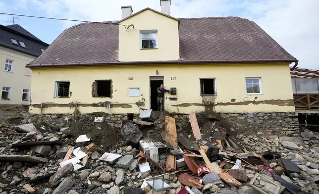 A man throws damaged goods and furniture off a house as residents return to clean up after recent floods in Mikulovice, Czech Republic, Thursday, Sept. 19, 2024. (AP Photo/Petr David Josek)