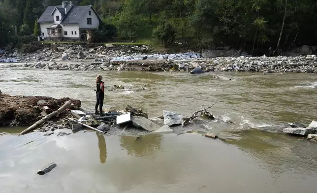 A woman stands by a river as residents return to clean up after recent floods near Pisecna, Czech Republic, Thursday, Sept. 19, 2024. (AP Photo/Petr David Josek)