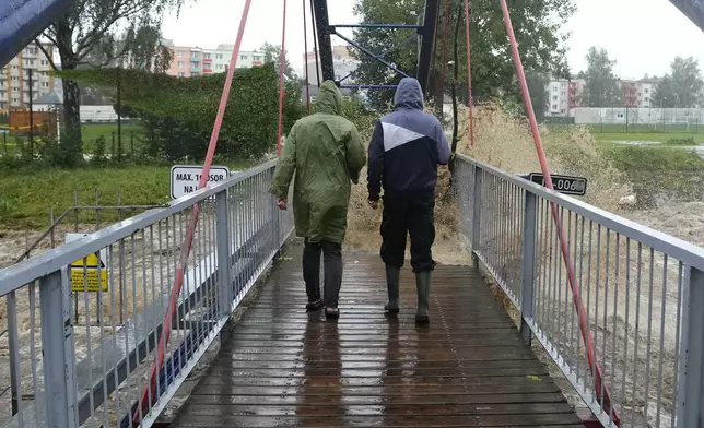 Residents cross a bridge during floods in Jesenik, Czech Republic, Sunday, Sept. 15, 2024. (AP Photo/Petr David Josek)