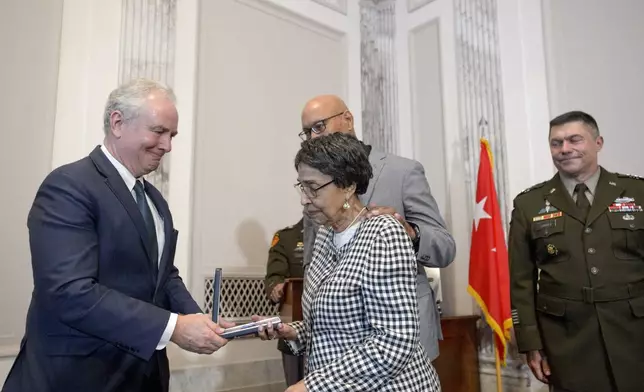 Sen. Chris Van Hollen, D-Md., left, presents the Distinguished Service Cross to Joann Woodson, center, and her son Steve Woodson, right, during a ceremony to posthumously award the Distinguished Service Cross to her husband U.S. Army Staff Sgt. Waverly Woodson, Jr., a medic who was part of the only Black combat unit to take part in the D-Day invasion of France during World War II, on Capitol Hill, in Washington, Tuesday, Sept. 24, 2024. (AP Photo/Rod Lamkey, Jr.)