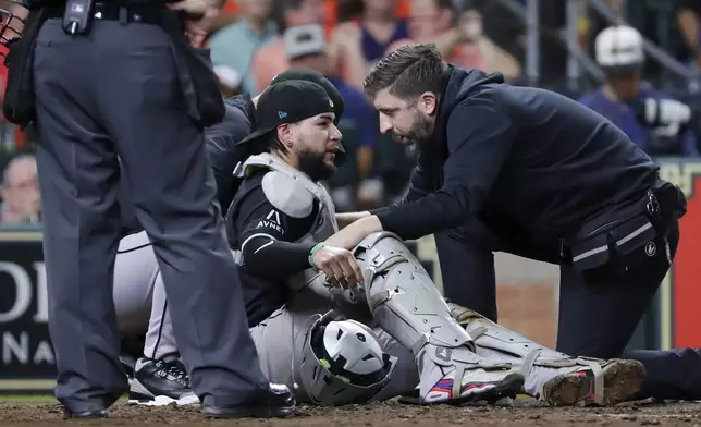 Arizona Diamondbacks catcher Jose Herrera, center, is tended to by trainers after being hit in the head on the back swing by Houston Astros' Kyle Tucker during the fifth inning of a baseball game, Friday, Sept. 6, 2024, in Houston. Herrera left the game after the incident. (AP Photo/Michael Wyke)