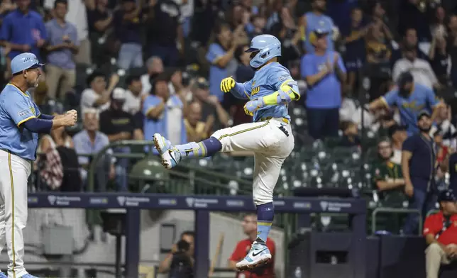 Milwaukee Brewers' William Contreras, right, reacts after hitting a three-run home run during the fifth inning of a baseball game against the Arizona Diamondbacks, Friday, Sept. 20, 2024, in Milwaukee. (AP Photo/Jeffrey Phelps)