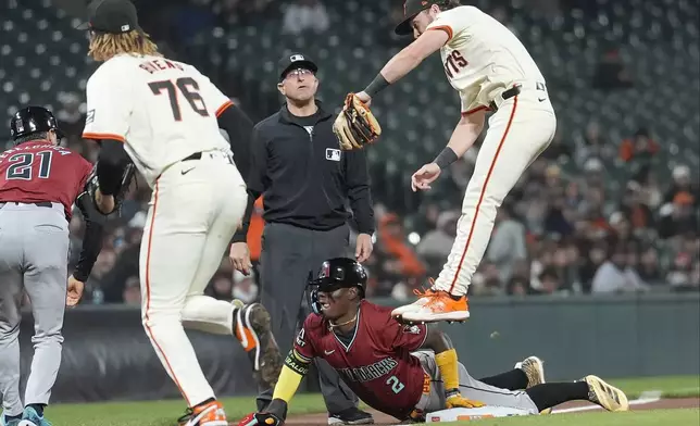 Arizona Diamondbacks' Geraldo Perdomo, bottom, slides safely into third base against San Francisco Giants pitcher Spencer Bivens (76) and third baseman Brett Wisely, top, during the seventh inning of a baseball game in San Francisco, Wednesday, Sept. 4, 2024. (AP Photo/Jeff Chiu)