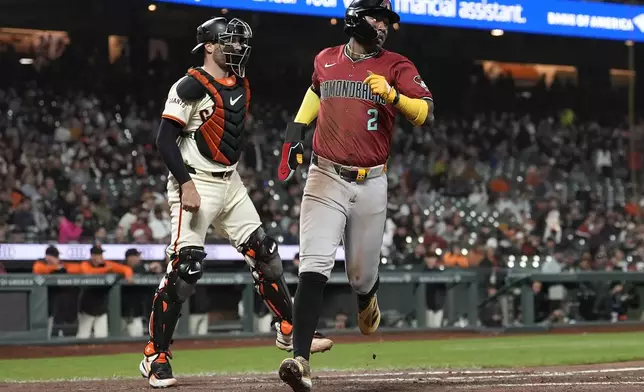 Arizona Diamondbacks' Geraldo Perdomo, right, scores past San Francisco Giants catcher Curt Casali during the seventh inning of a baseball game in San Francisco, Wednesday, Sept. 4, 2024. (AP Photo/Jeff Chiu)