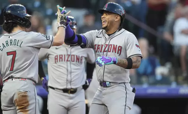 Arizona Diamondbacks' Corbin Carroll, left, congratulates Ketel Marte as he crosses home plate after hitting a two-run home run off Colorado Rockies starting pitcher Antonio Senzatela in the first inning of a baseball game, Monday, Sept. 16, 2024, in Denver. (AP Photo/David Zalubowski)