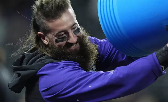 Colorado Rockies' Charlie Blackmon smiles as he tries to douse television analyst Ryan Spilborghs after the Rockies' walkoff victory over the Arizona Diamondbacks in a baseball game Monday, Sept. 16, 2024, in Denver. (AP Photo/David Zalubowski)