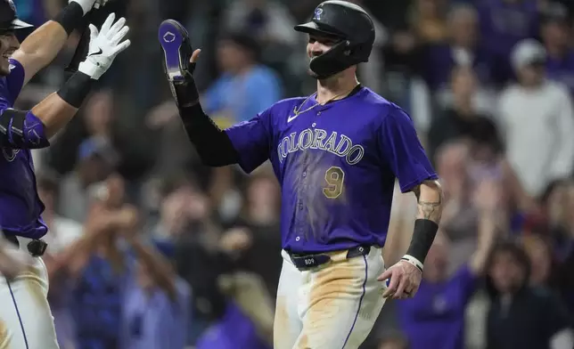 Colorado Rockies' Brenton Doyle is congratulated after scoring the winning run on a force out hit into by Brendan Rodgers in the ninth inning of a baseball game against the Arizona Diamondbacks, Monday, Sept. 16, 2024, in Denver. (AP Photo/David Zalubowski)