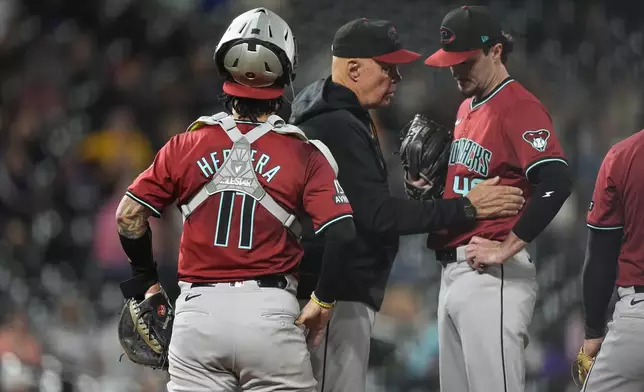 Arizona Diamondbacks pitching coach Brent Strom, center, confers with relief pitcher Blake Walston as catcher Jose Herrera looks on after Walston gave up an RBI single to Colorado Rockies' Brendan Rodgers in the eighth inning of a baseball game Tuesday, Sept. 17, 2024, in Denver. (AP Photo/David Zalubowski)