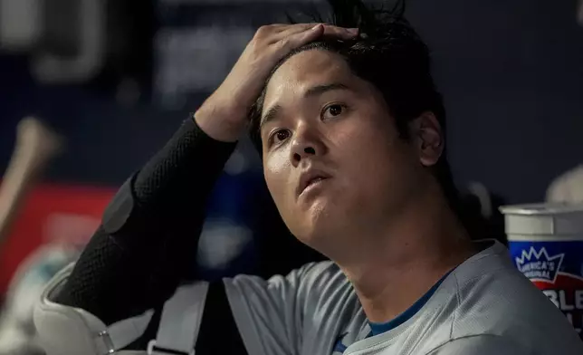 Los Angeles Dodgers two-way player Shohei Ohtani (17) sits in the dugout in the fourth inning of a baseball game against the Atlanta Bravess, Friday, Sept. 13, 2024, in Atlanta. (AP Photo/Mike Stewart)