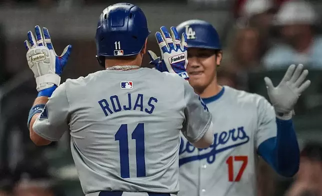 Los Angeles Dodgers' Miguel Rojas (11) celebrates his solo homer with Shohei Ohtani (17) in the third inning of a baseball game against the Atlanta Braves, Friday, Sept. 13, 2024, in Atlanta. (AP Photo/Mike Stewart)