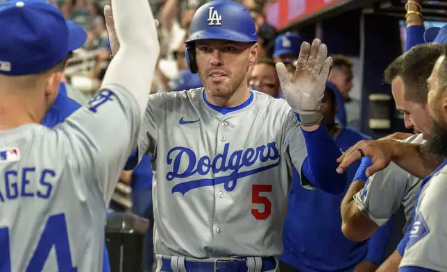 Los Angeles Dodgers' Freddie Freeman celebrates in the dugout after hitting three-run home run in the seventh inning of a baseball game against the Atlanta Braves, Monday, Sept. 16, 2024, in Atlanta. (AP Photo/Jason Allen)