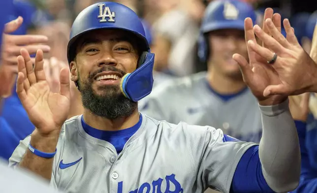 Los Angeles Dodgers' Teoscar Hernández celebrates in the dugout after Freddie Freeman hit a three-run home run in the seventh inning of a baseball game against the Atlanta Braves, Monday, Sept. 16, 2024, in Atlanta. (AP Photo/Jason Allen)