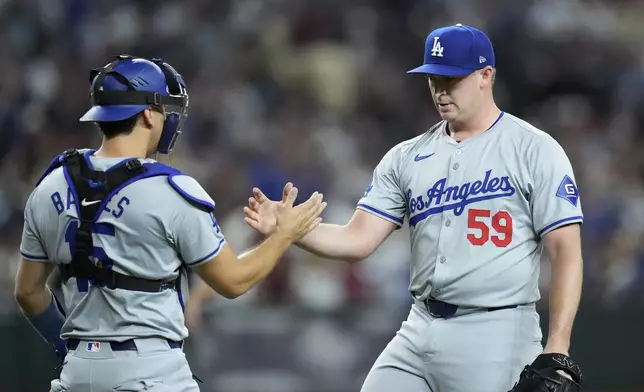 Los Angeles Dodgers relief pitcher Evan Phillips (59) slaps hands with catcher Austin Barnes, left, after the final out of a baseball game against the Arizona Diamondbacks, Saturday, Aug. 31, 2024, in Phoenix. (AP Photo/Ross D. Franklin)