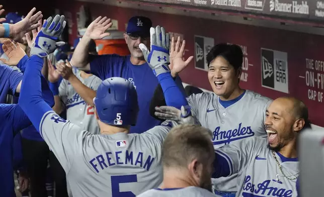 Los Angeles Dodgers' Freddie Freeman (5) celebrates his home run against the Arizona Diamondbacks with teammates, including Mookie Betts, right, and Shohei Ohtani, second from right, during the first inning of a baseball game Saturday, Aug. 31, 2024, in Phoenix. (AP Photo/Ross D. Franklin)