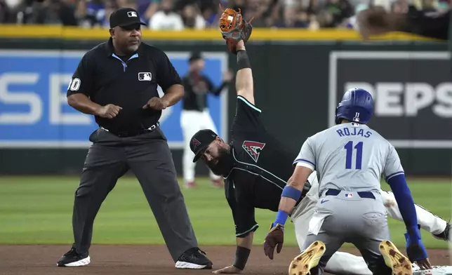 Arizona Diamondbacks second base Luis Guillorme, center, holds up the ball after trying to tag out Los Angeles Dodgers' Miguel Rojas (11) in the third inning during a baseball game, Monday, Sept. 2, 2024, in Phoenix. (AP Photo/Rick Scuteri)