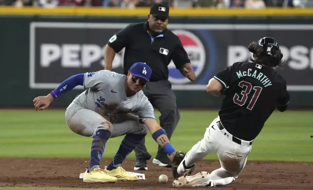 Los Angeles Dodgers shortstop Miguel Rojas, front left, tags out Arizona Diamondbacks' Jake McCarthy, right, on a steal-attempt in the sixth inning during a baseball game, Monday, Sept. 2, 2024, in Phoenix. (AP Photo/Rick Scuteri)