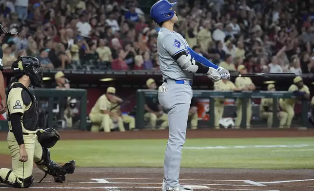 Los Angeles Dodgers designated hitter Shohei Ohtani watches the flight his home run as Arizona Diamondbacks catcher Adrian Del Castillo, left, looks on during the first inning of a baseball game, Saturday, Aug. 31, 2024, in Phoenix. (AP Photo/Ross D. Franklin)