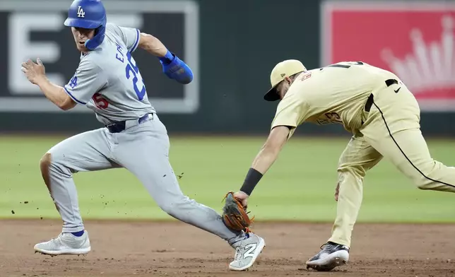 Los Angeles Dodgers' Tommy Edman, left, is tagged out in a rundown between second and third base by Arizona Diamondbacks second baseman Luis Guillorme during the eighth inning of a baseball game Saturday, Aug. 31, 2024, in Phoenix. (AP Photo/Ross D. Franklin)