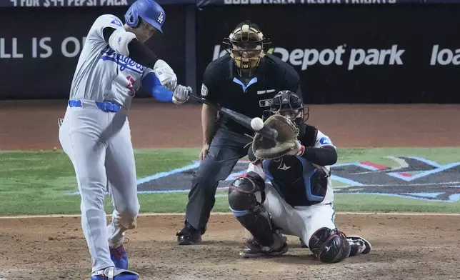 Los Angeles Dodgers' Shohei Ohtani, of Japan, hits a home run, scoring Max Muncy and Chris Taylor, during the ninth inning of a baseball game against the Miami Marlins, Thursday, Sept. 19, 2024, in Miami. (AP Photo/Wilfredo Lee)