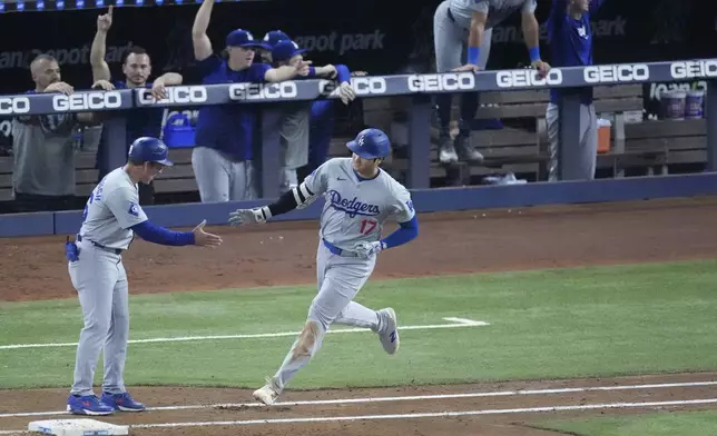 Los Angeles Dodgers first base coach Clayton McCullough, left, congratulates Shohei Ohtani (17) after Ohtani hit a home run scoring Andy Pages, during the sixth inning of a baseball game against the Miami Marlins, Thursday, Sept. 19, 2024, in Miami. (AP Photo/Wilfredo Lee)