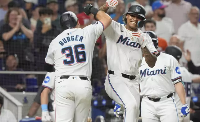 Miami Marlins' Cristian Pache and Jake Burger (36) celebrate Burger's two-run home run doing the eighth inning of a baseball game against the Los Angeles Dodgers, Tuesday, Sept. 17, 2024, in Miami. (AP Photo/Marta Lavandier)