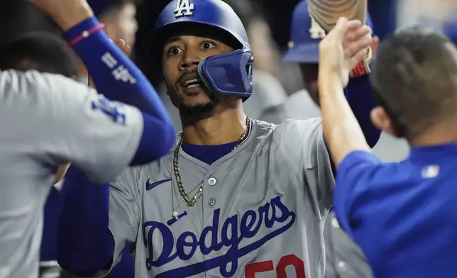 Los Angeles Dodgers' Mookie Betts (50) scores on a sacrifice hit by Freddie Freeman during the fifth inning of a baseball game against the Miami Marlins, Tuesday, Sept. 17, 2024, in Miami. (AP Photo/Marta Lavandier)