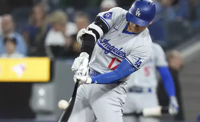 Los Angeles Dodgers designated hitter Shohei Ohtani (17) hits a solo home run next to Toronto Blue Jays catcher Danny Jansen during the first inning of a baseball game Friday, April 26, 2024, in Toronto. (Nathan Denette/The Canadian Press via AP)