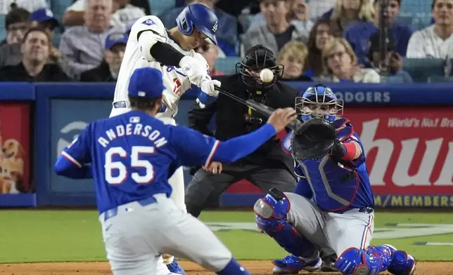 Los Angeles Dodgers' Shohei Ohtani, second from left, hits a two-run home run as Texas Rangers relief pitcher Grant Anderson, left, watches along with catcher Jonah Heim, right, and home plate umpire Nick Mahrley during the sixth inning of a baseball game Tuesday, June 11, 2024, in Los Angeles. (AP Photo/Mark J. Terrill)