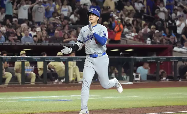 Los Angeles Dodgers designated hitter Shohei Ohtani, of Japan, claps has he rounds the bases after hitting a home run against the Arizona Diamondbacks during the eighth inning of a baseball game Friday, Aug. 30, 2024, in Phoenix. (AP Photo/Ross D. Franklin)