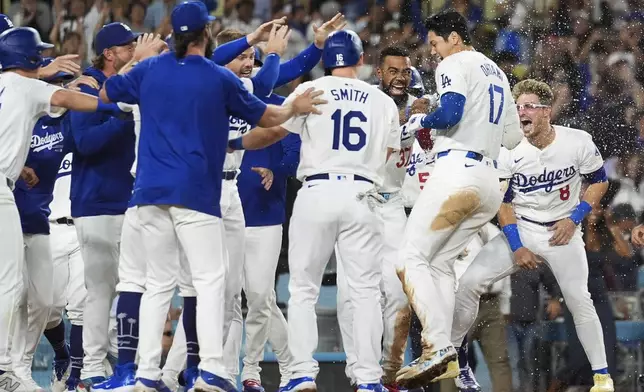 Los Angeles Dodgers designated hitter Shohei Ohtani (17) celebrates with teammates after hitting a grand slam during the ninth inning of a baseball game against the Tampa Bay Rays in Los Angeles, Friday, Aug. 23, 2024. The Dodgers won 7-3. (AP Photo/Ashley Landis)