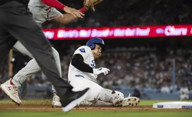 Los Angeles Dodgers' Shohei Ohtani, right, steals third base during the fifth inning of a baseball game against the Philadelphia Phillies in Los Angeles, Monday, Aug. 5, 2024. (AP Photo/Kyusung Gong)