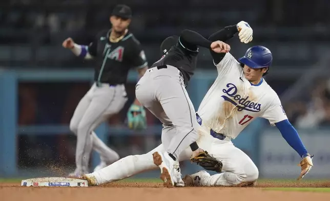 Los Angeles Dodgers' Shohei Ohtani, right, steals second base past Arizona Diamondbacks shortstop Kevin Newman during the sixth inning of a baseball game Tuesday, May 21, 2024, in Los Angeles. (AP Photo/Marcio Jose Sanchez)