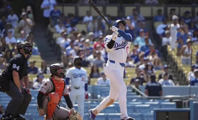 Los Angeles Dodgers designated hitter Shohei Ohtani, right, hits a home run during the eighth inning of a baseball game against the San Francisco Giants in Los Angeles, Thursday, July 25, 2024. (AP Photo/Eric Thayer)