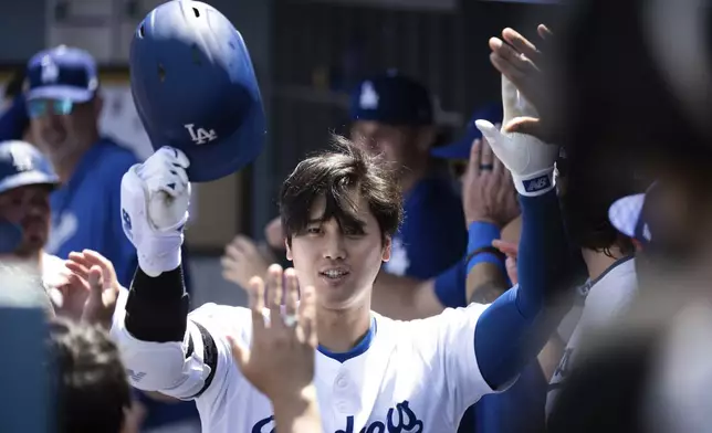 Los Angeles Dodgers' Shohei Ohtani celebrates after his two-run home run in the dugout during the third inning of a baseball game against the New York Mets in Los Angeles, Sunday, April 21, 2024. (AP Photo/Kyusung Gong)