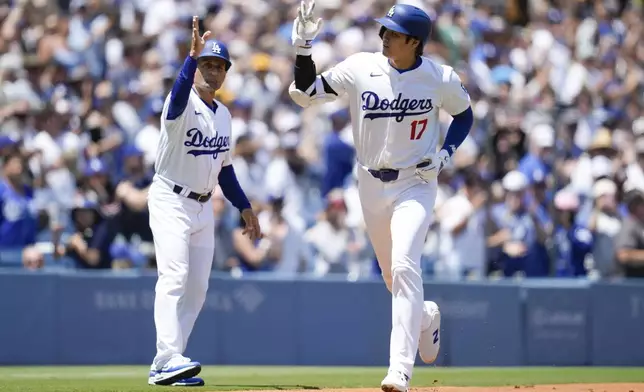 Los Angeles Dodgers designated hitter Shohei Ohtani celebrates with third base coach Dino Ebel (91) after hitting a home run during the first inning of a baseball game against the Atlanta Braves in Los Angeles, Sunday, May 5, 2024. (AP Photo/Ashley Landis)