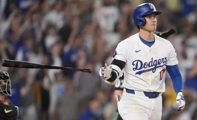 Los Angeles Dodgers designated hitter Shohei Ohtani tosses his bat after hitting a go-ahead two-run home run during the seventh inning of a baseball game against the Arizona Diamondbacks, Tuesday, July 2, 2024, in Los Angeles. (AP Photo/Ryan Sun)