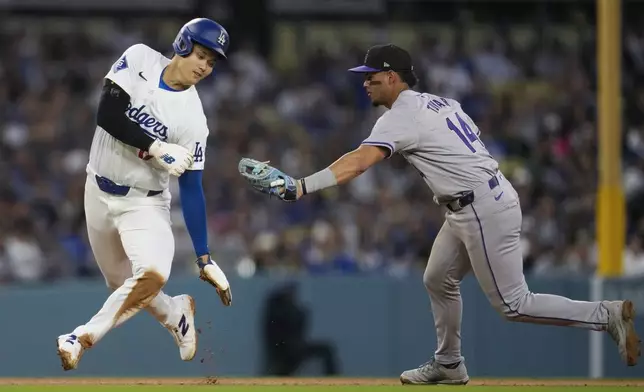 Los Angeles Dodgers designated hitter Shohei Ohtani (17) is caught stealing third by Colorado Rockies shortstop Ezequiel Tovar (14) during the third inning of a baseball game in Los Angeles, Saturday, June 1, 2024. (AP Photo/Ashley Landis)