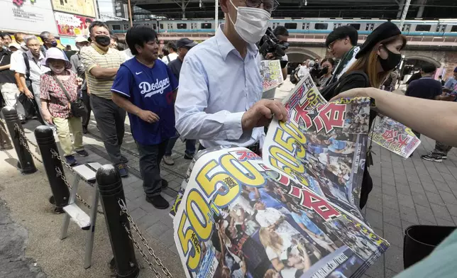 Pedestrians line up to obtain an extra edition of the Sports Nippon newspaper reporting on the Los Angeles Dodgers' Shohei Ohtani becoming the first player in major league history with 50 home runs and 50 stolen bases in a season, Friday, Sept. 20, 2024, in Tokyo. (AP Photo/Eugene Hoshiko)